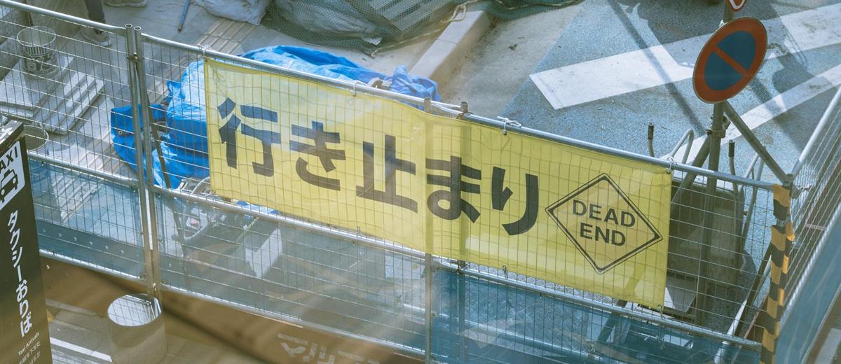 工事現場の柵に掛けられた「行き止まり DEAD END」の黄色い垂れ幕
