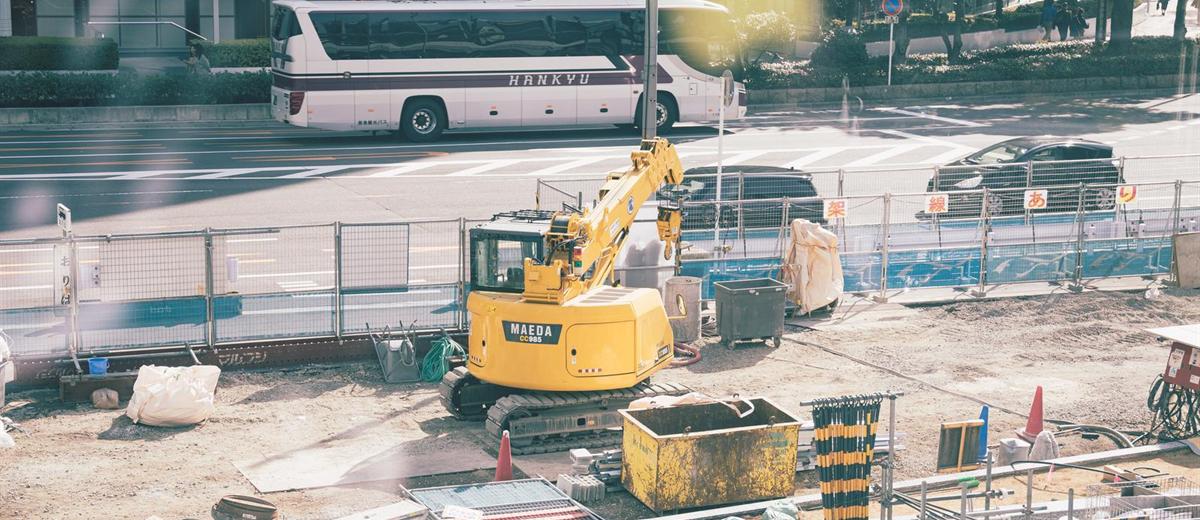 大阪の街なかの建設現場。小型の油圧ショベルと路線バス