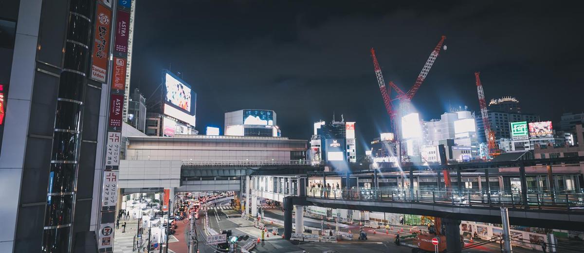 夜の渋谷駅南口。工事のクレーンとネオン看板が並ぶ