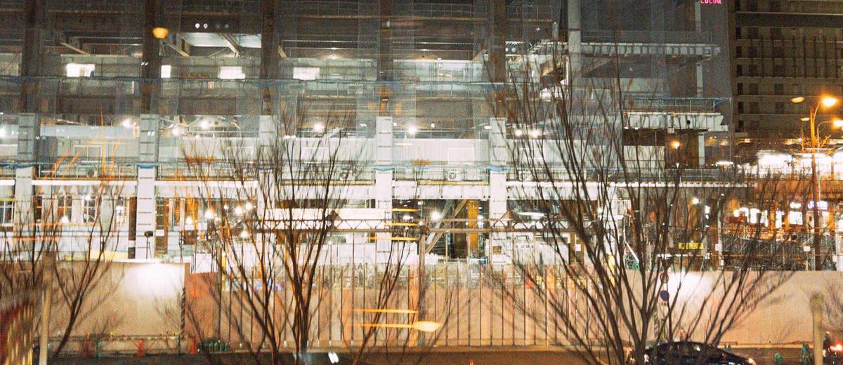 夜間に照明がついた建設中の建物と足場